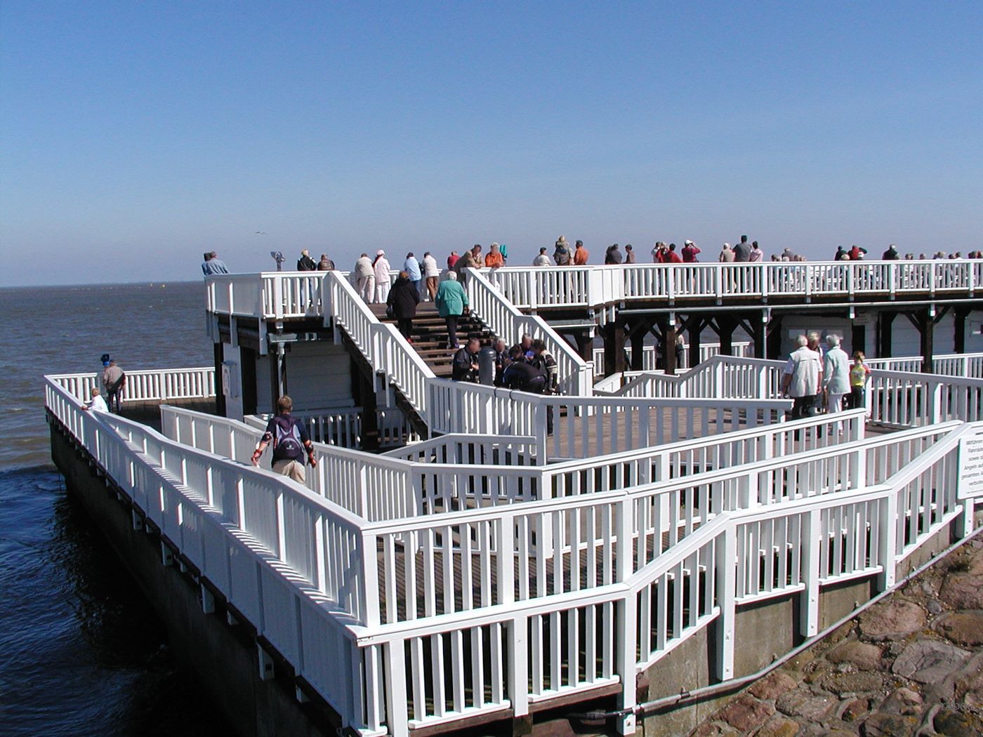 The two-storey Alte Liebe observation platform in Cuxhaven with visitors on the upper deck under a blue sky