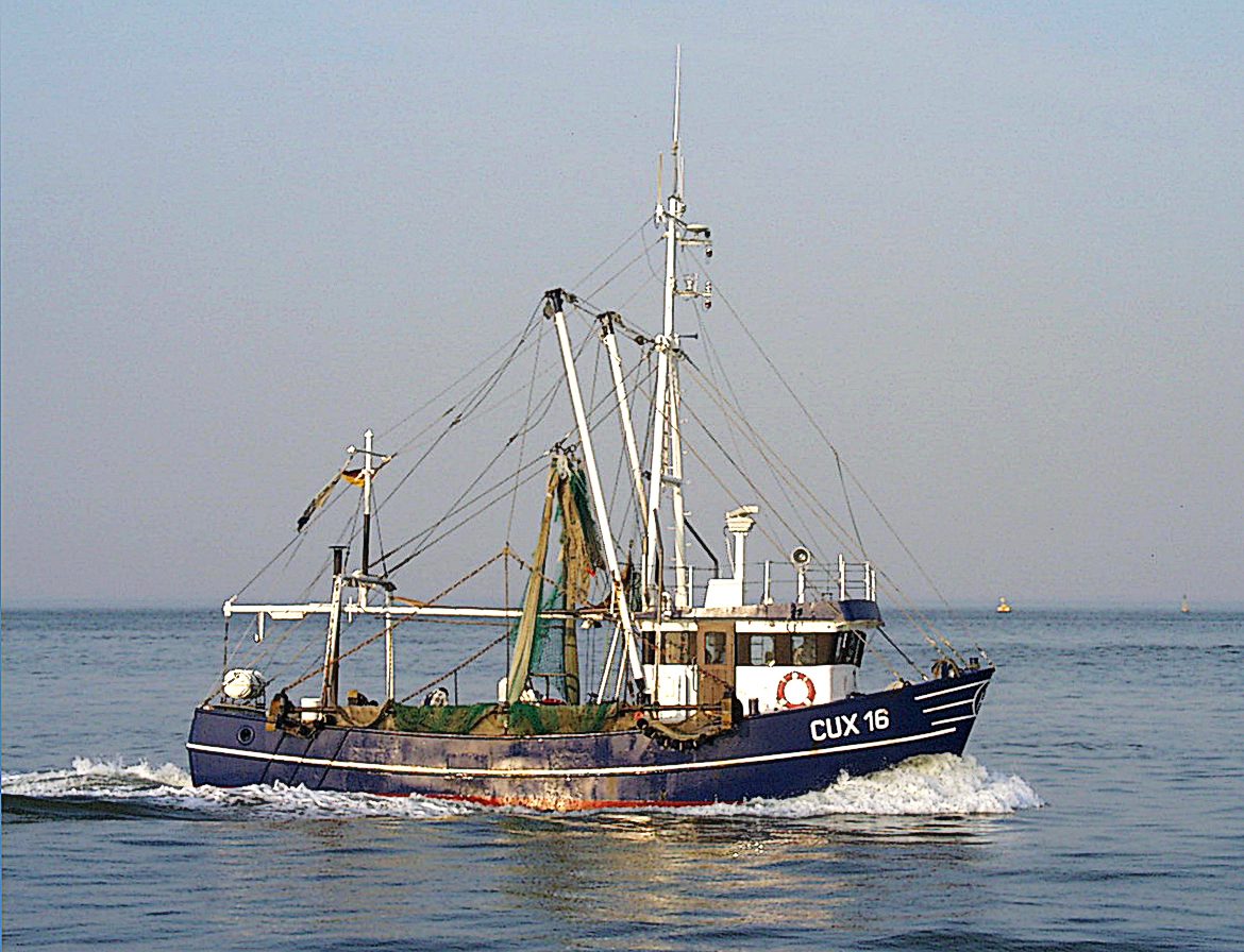Blue shrimp cutter CUX 16 with raised net booms sailing on the North Sea off Cuxhaven