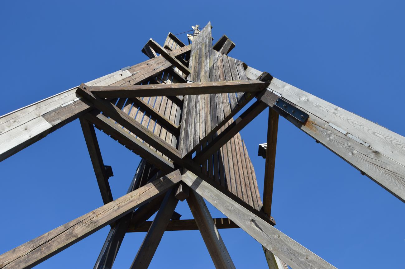Blick von unten steil nach oben in die gekreuzte Holzkonstruktion der Kugelbake vor strahlend blauem Himmel