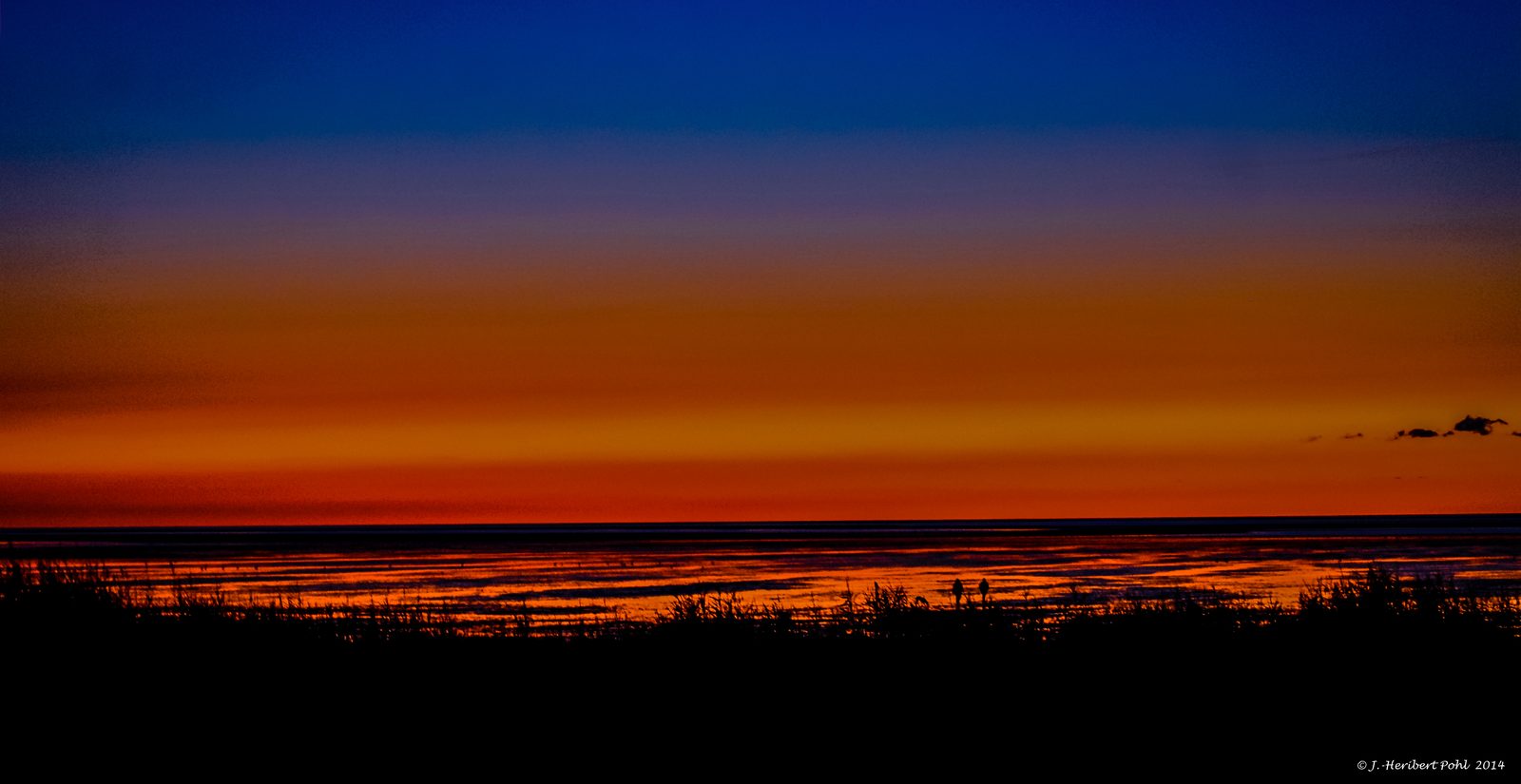Sunset over the mudflats at Sahlenburg beach near Cuxhaven, beach chairs in the foreground