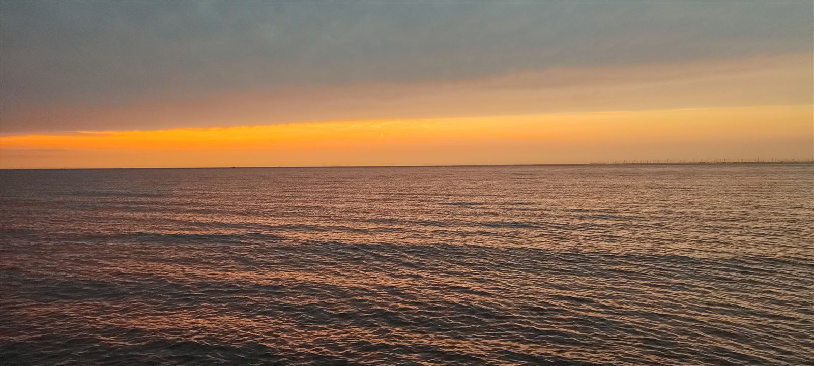 Goldener Sonnenuntergang über der Nordsee Otterndorf – offene See, ruhige Wasseroberfläche, Windräder am Horizont